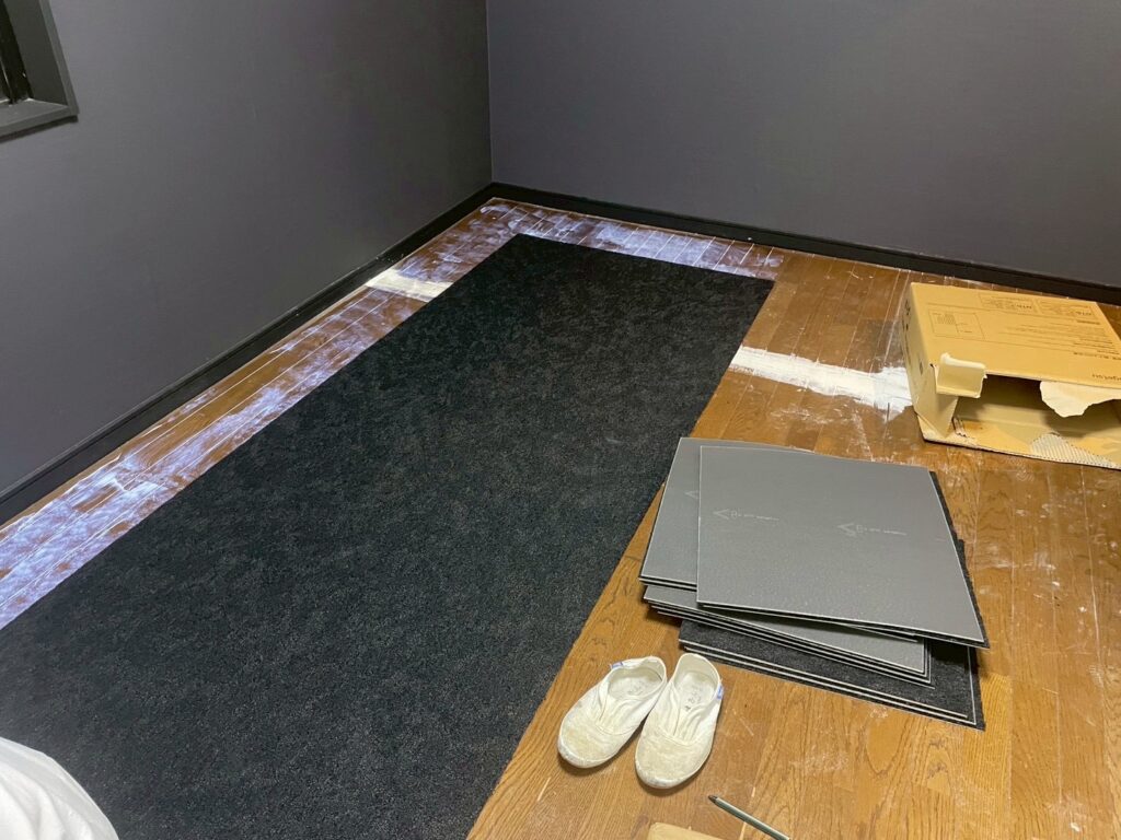 江東区のマンションでカーペット施工前の下地シート（アンダーレイ）を敷いている様子。床の凹凸を防ぎ、防音性とクッション性を高める工程。
