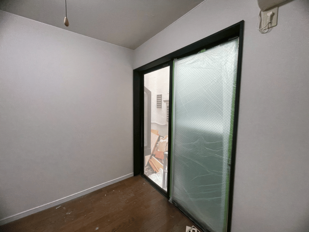 【施工レポート】クロス張りで部屋が生まれ変わる!アクセントクロスの魅力 6 クロス張り後の窓側の様子。黒い建具とダークグレーのアクセントクロスが調和したスタイリッシュな室内。