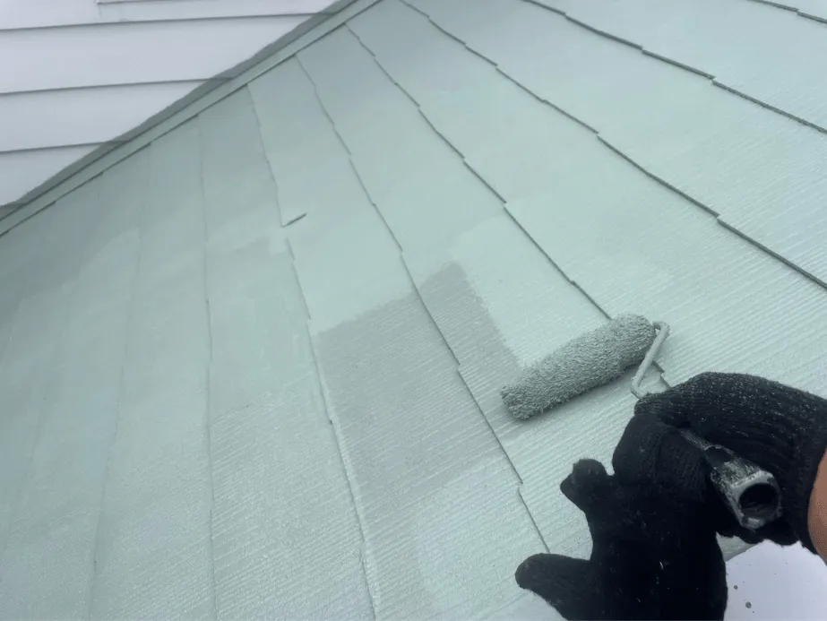 屋根の下塗り作業の様子。ローラーでプライマーを均一に塗布し、密着性を高めている。