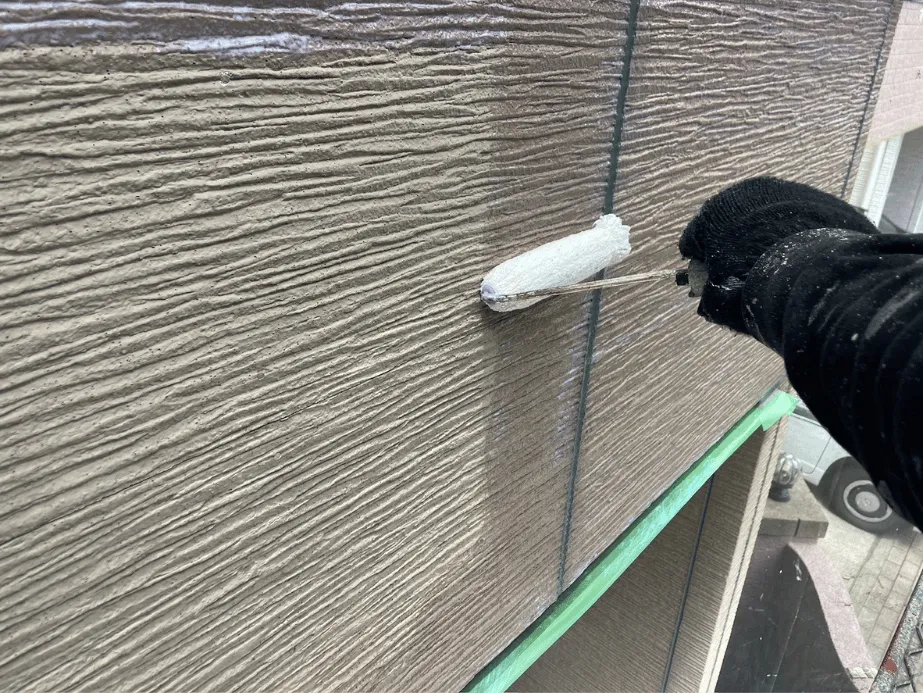 サイディング外壁に下塗り材をローラーで均一に塗布している作業の様子