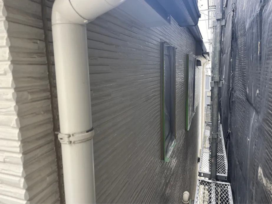 【施工レポート】外壁の下塗り|塗装の耐久性を決める最重要工程 4 外壁の下塗り後、養生した窓まわりと縦樋が整った状態のサイディング外壁の様子