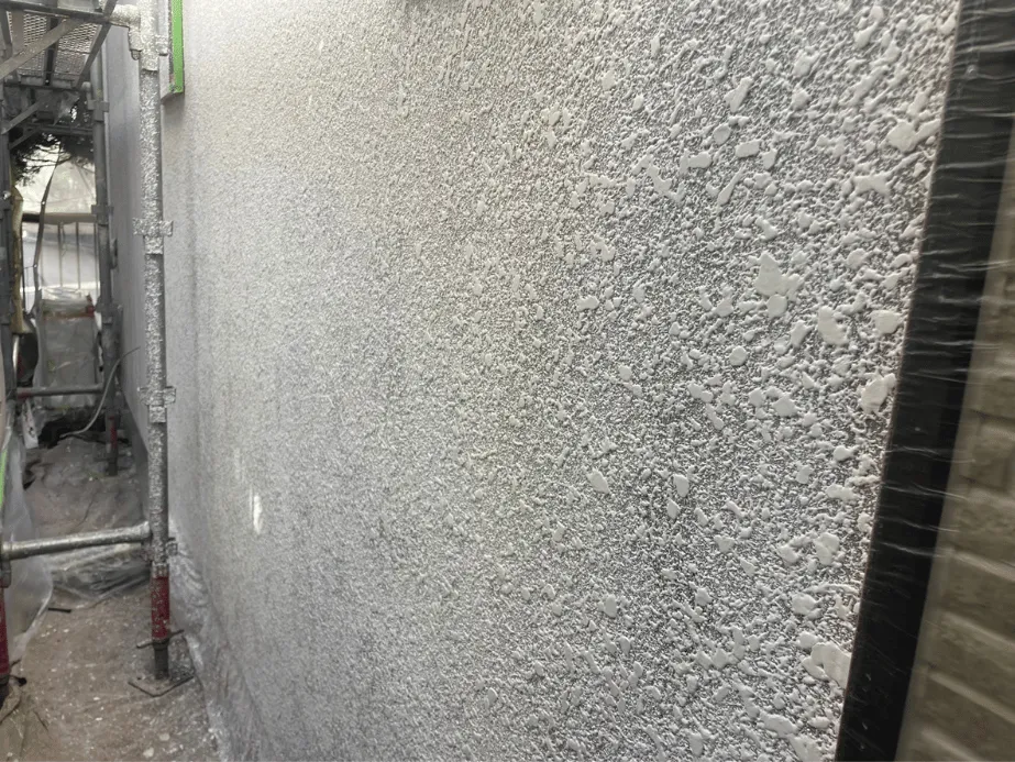 【施工レポート】吹付塗装で美しい仕上がりに|ローラーとの使い分け 3 リシン外壁への吹付塗装の様子|細かい霧状の塗料が均一に付着していく工程